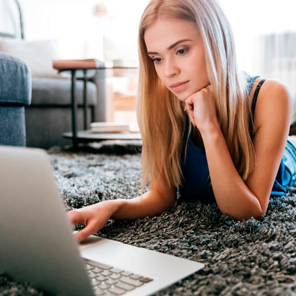 Eine junge Frau recherchiert auf dem Laptop wie man die Qualität von Teppichen erkennen kann